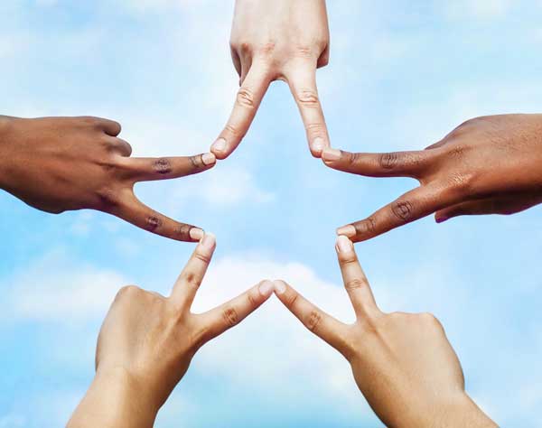 Group of multi-ethinic people's hands forming star shape.